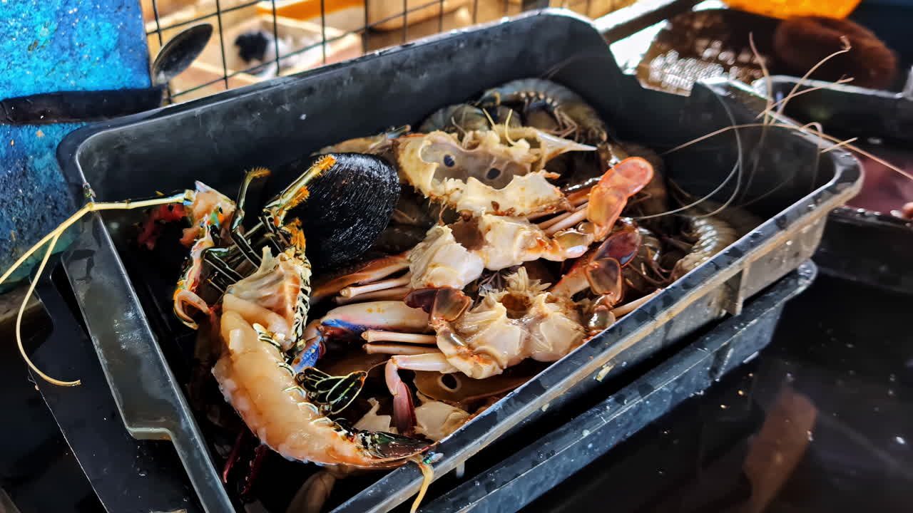 Closeup view of a shellfish basket with a woman's hands working in the background at a local fish market in Weligama Sri Lanka during summer vacation