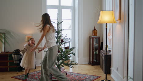 active family playing at new year tree room. mother running away from daughter