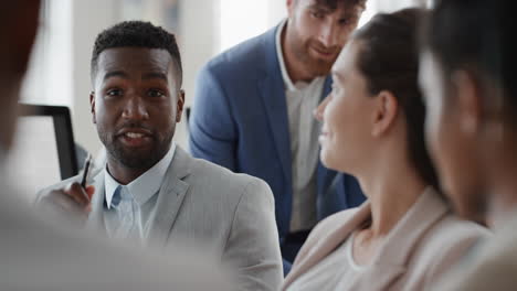 african american businessman chatting with colleagues in office meeting having conversation sharing ideas with diverse corporate group in workplace