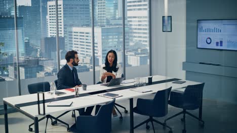 businesspeople in modern office: businesswoman and businessman use laptop computer, talk. top manager and partner investor discuss e-commerce software global investment strategy. elevating wide shot