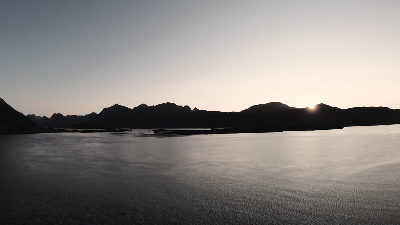 물을 바라보며 바다에 가까운 해안으로 날아가는 것, 배경의 산, 슬로모션으로 그 뒤에 지는 태양