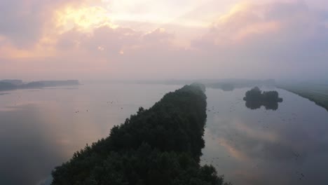 Vista-Aérea-De-Drones-De-Aguas-Y-Ríos-Con-Cielo-Naranja-Al-Amanecer-Con-Niebla-Ligera