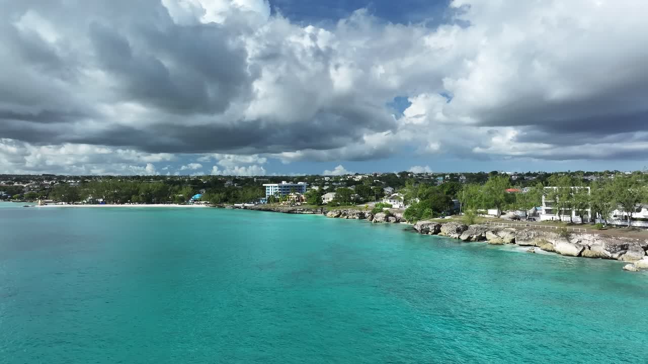 Drone shot of turquoise Caribbean waters and coastal homes under dramatic clouds in Barbados