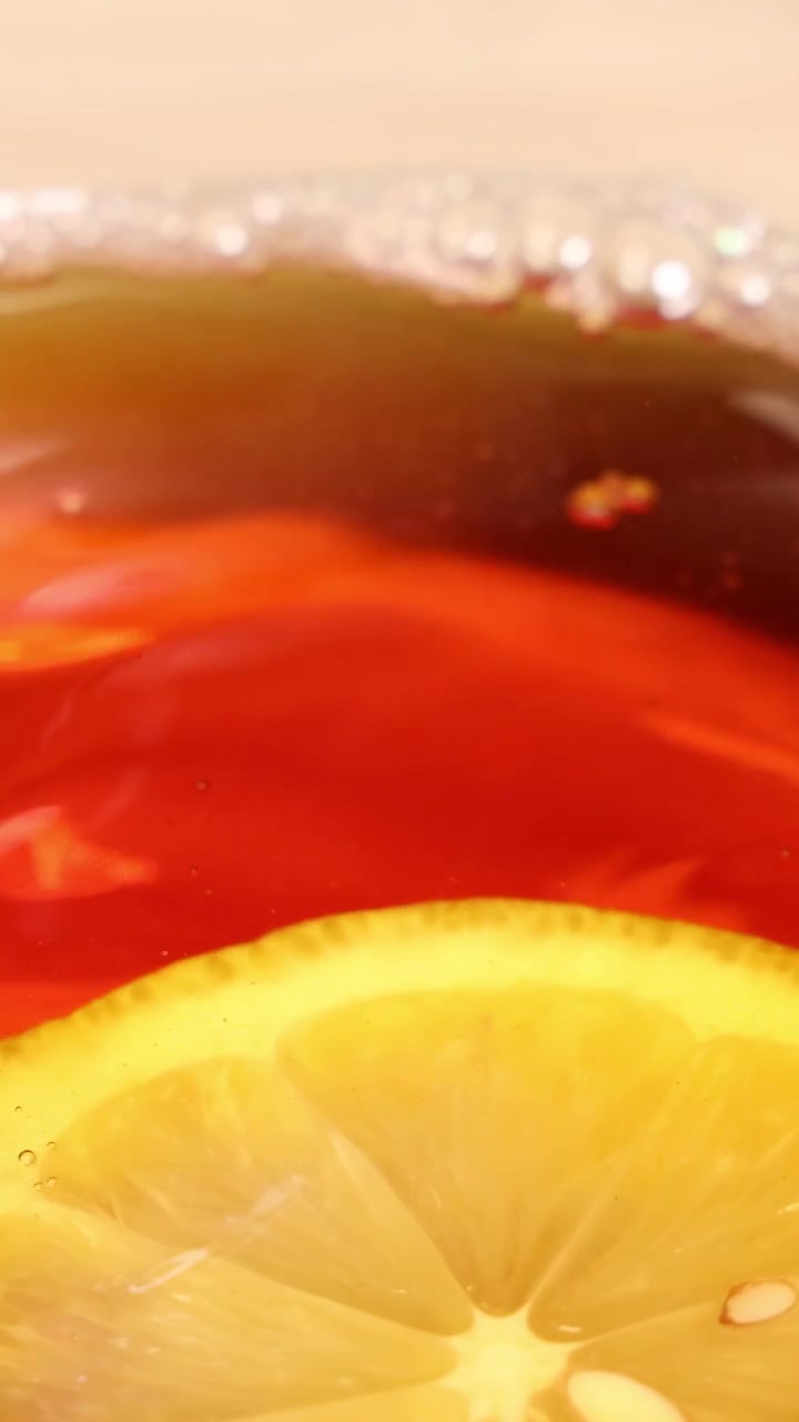 Una fetta di limone schizza in una tazza di tè, creando increspature e bolle in una vista ravvicinata