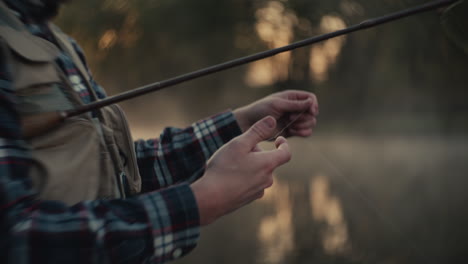 fisherman tying fly fishing line at sunrise