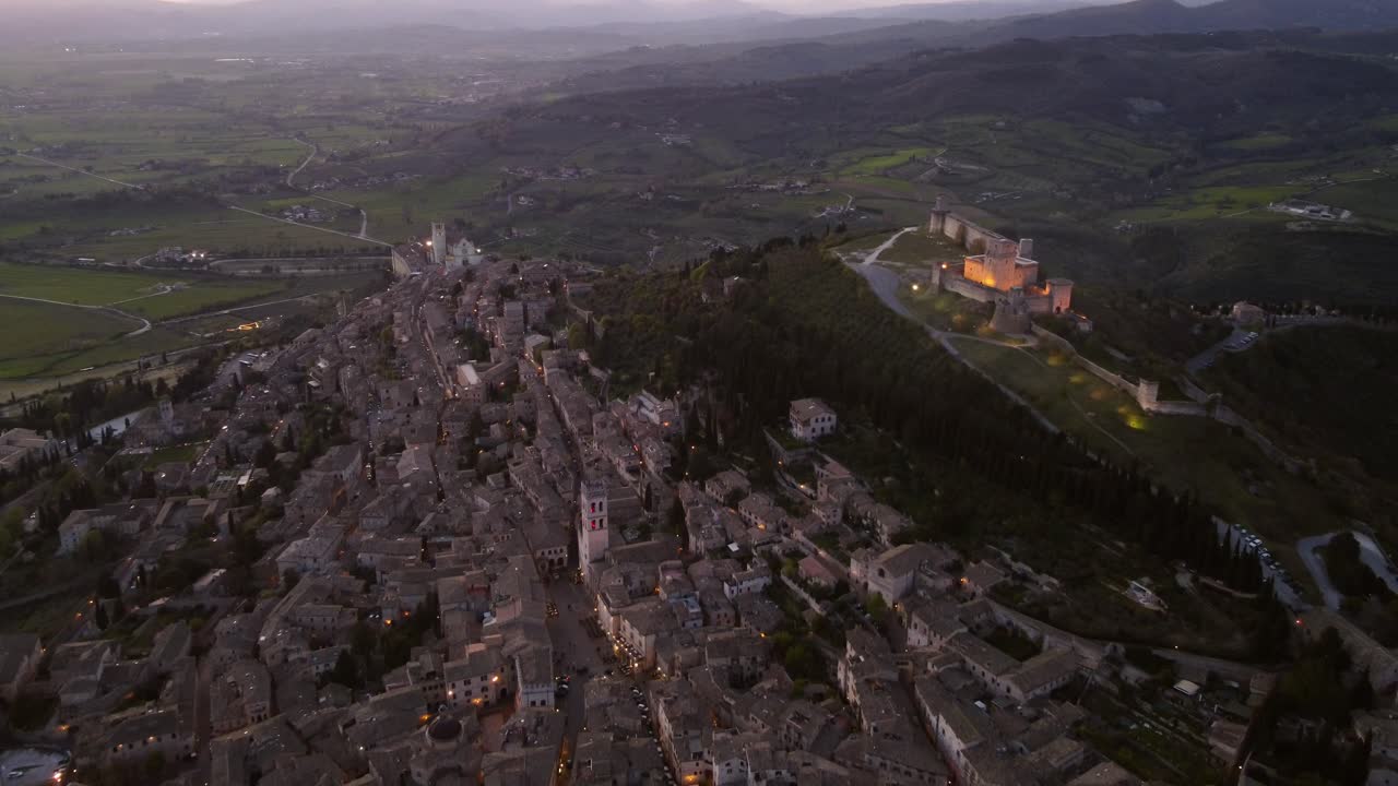 Aerial view of Assisi city in Umbria, Italy at twilight, flying backwards, 4K