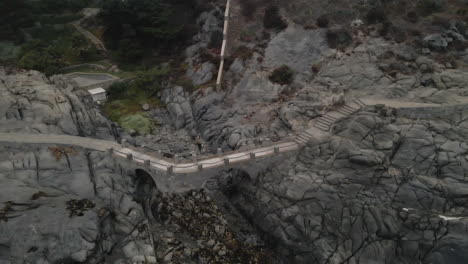 aerial - stone bridge on coast of zapallar, valparaiso, chile, wide circle shot