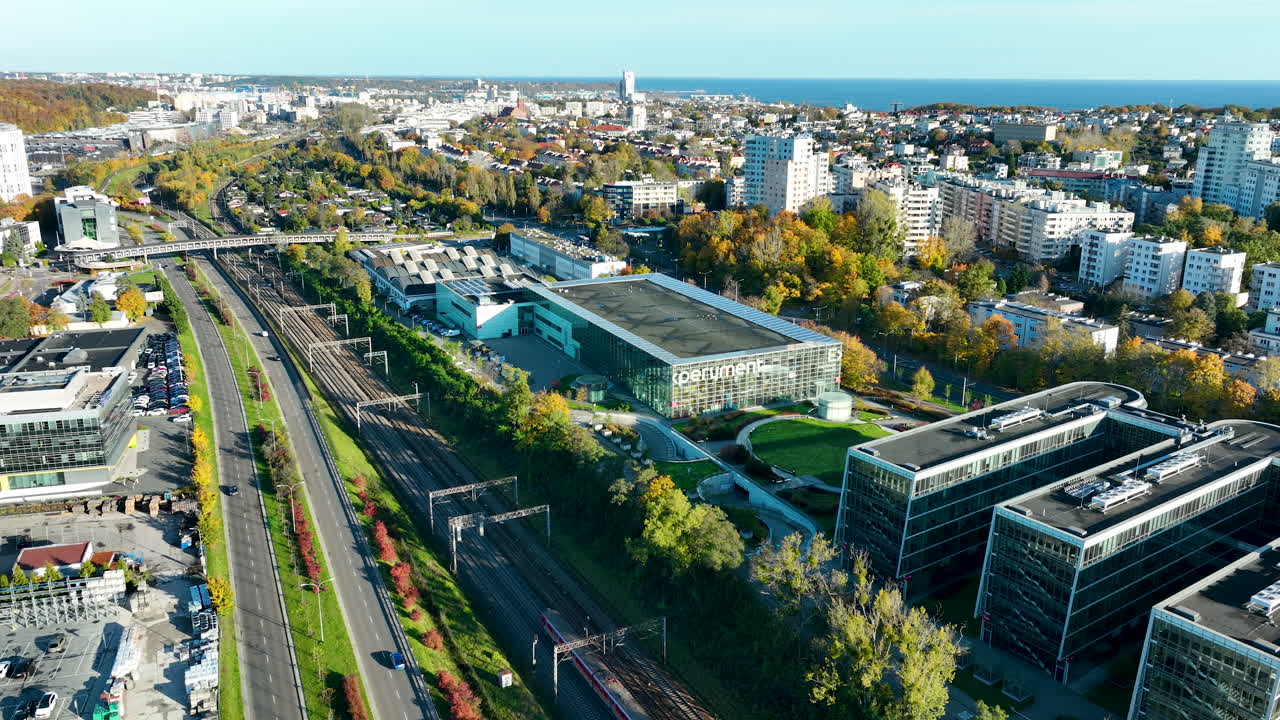 Aerial panorama of Gdynia with modern offices, stadium, and sea horizon visible in the distance on a sunny day