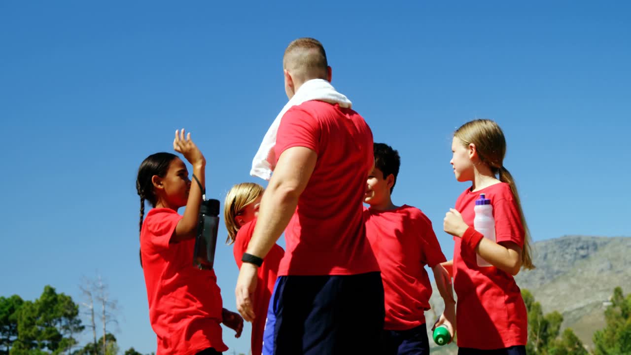 트레이너 와 아이 들 은 공원 에서 서로 다섯 개 를 주고 있다