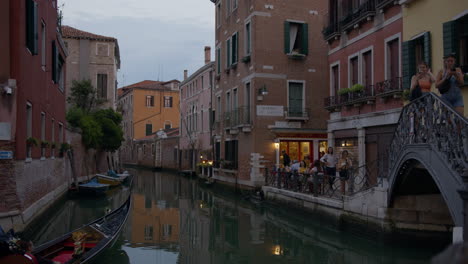 una góndola flota por un estrecho canal en venecia, italia, al atardecer.