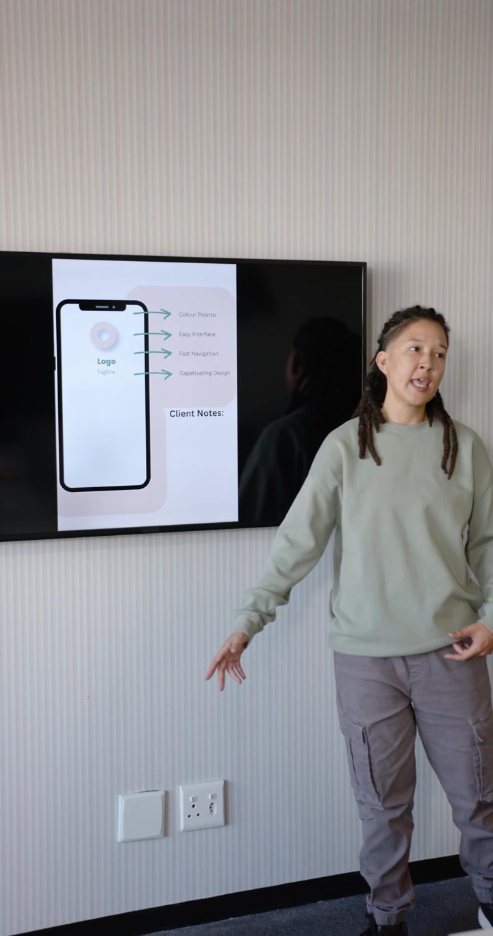 Vertical video: Nonbinary host presenting after TV slide appearing, in sage tee gesturing