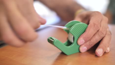 tome a mano una tira de cinta adhesiva del dispensador de plástico, espacio de trabajo de oficina