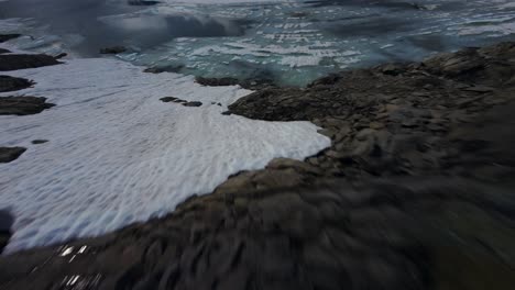 fast fpv aerial flying across snow covered landscape near grimsel pass in switzerland towards frozen lake