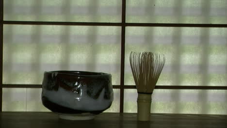 tazón de té japonés en el estante frente a la ventana de papel de morera