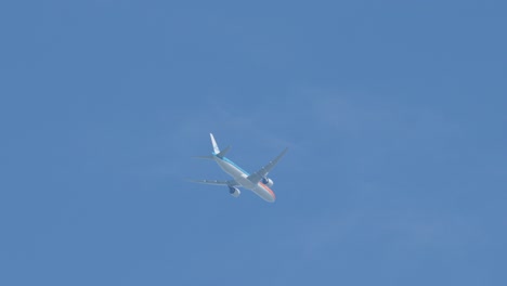 passenger airplane flies overhead in daylight, viewed from below, with smooth camera tracking movement