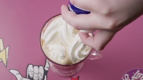 spraying whipped cream over a vanilla milkshake