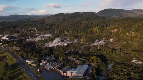 Pohutu-Geyser-With-Smoke-In-Whakarewarewa,-Rotorua,-New-Zealand-With-Tourist-Attractions-Nearby