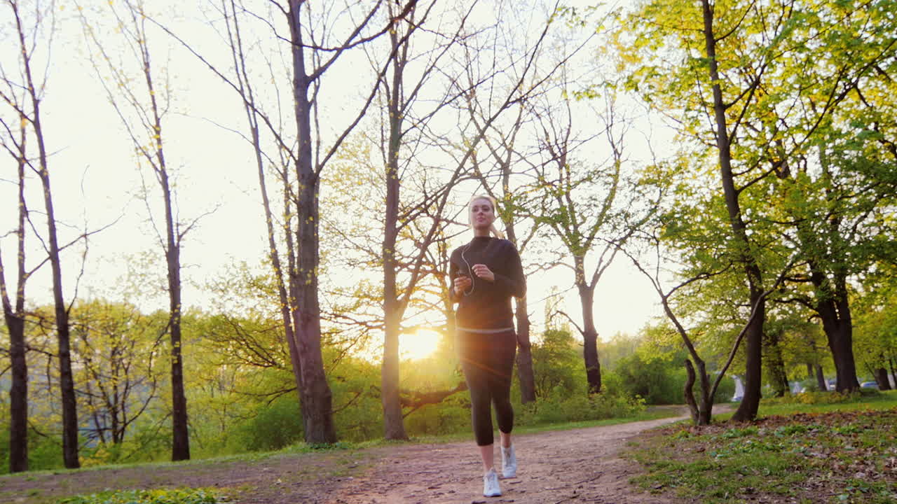 mujer joven trotando en el bosque el sol brilla maravillosamente en la cámara