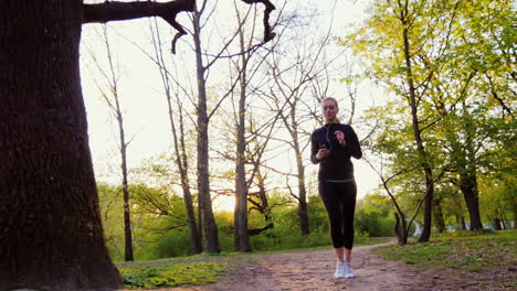 Junge-Frau-Beim-Joggen-Im-Wald-Die-Sonne-Scheint-Schön-In-Die-Kamera