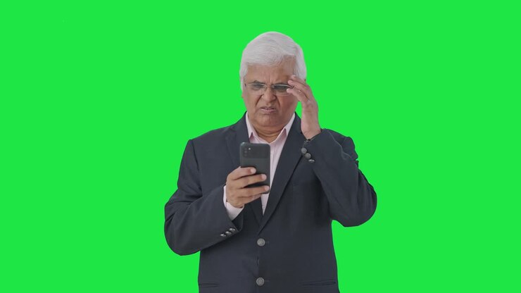 el gerente senior indio tenso usando la pantalla verde del teléfono móvil
