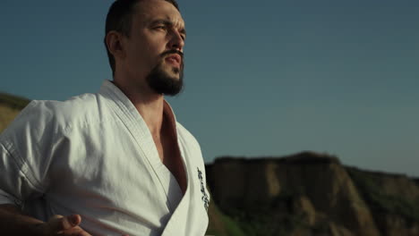 maestro de taekwondo practicando artes marciales cerca de la colina. hombre ejercitando postura de combate
