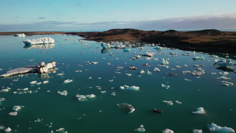 jokulsarlon glacial lagoon in south iceland - crushed icebergs scattered in the blue water under the blue sky - close-up drone shot