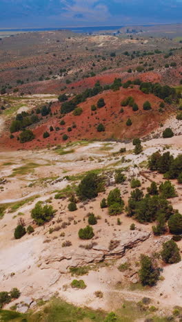Travertine rough uneven landscape with brown hills and light ground between them. Hazy blue mountainous horizon at backdrop. Vertical video