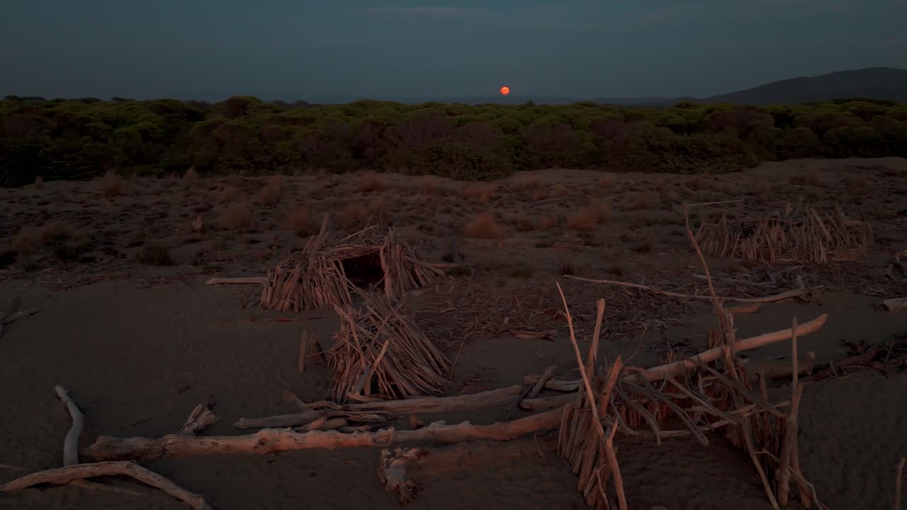 Tipi in legno in riva al mare su una spiaggia naturale al tramonto.