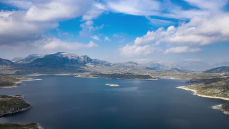 Clouds-whirling-above-the-Kjelevant-lake,-casting-shadows-on-the-land-and-water