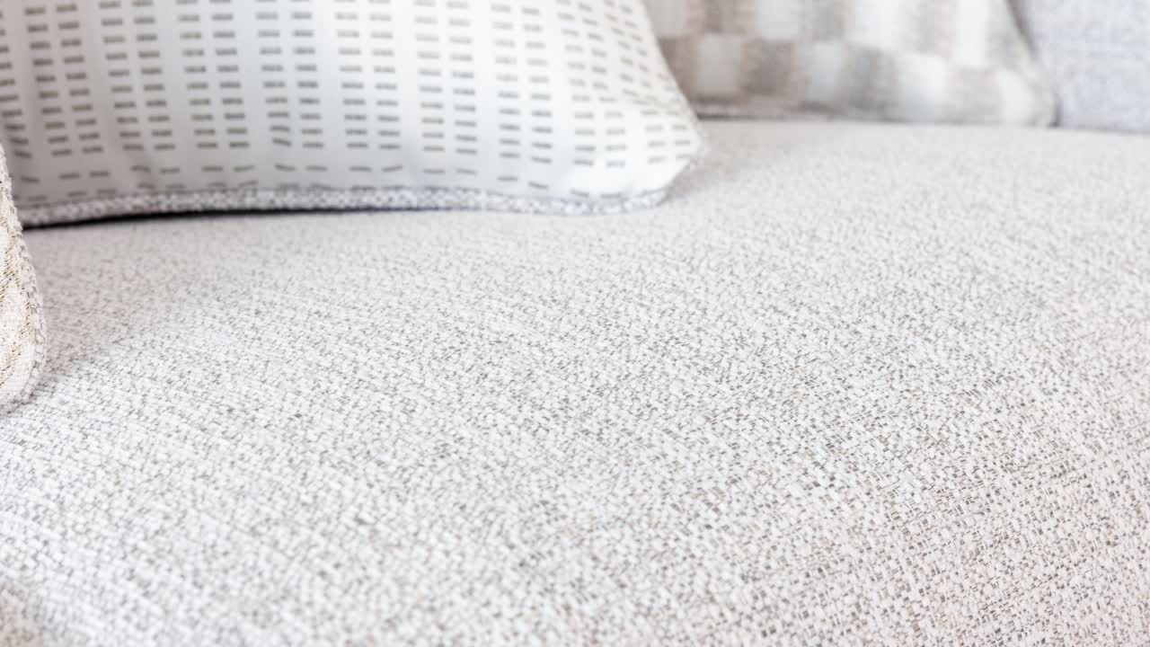 Camera sweeps along spotless upholstery, highlighting soft pillows and clean lines