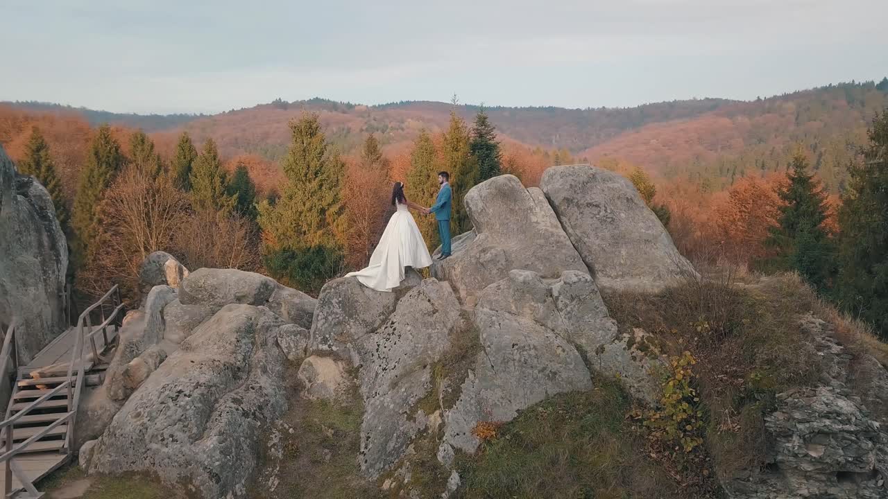 los recién casados están en una ladera alta de la montaña. el novio y la novia.