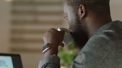 Joven-Hombre-De-Negocios-Afroamericano-Usando-Una-Computadora-Portátil-En-Una-Cafetería-Bebiendo-Café-Escribiendo-Documentos-Trabajando-En-Línea-Enviando-Correo-Electrónico-Empresario-Independiente-Disfrutando-De-Una-Mañana-Relajada-Trabajando-En-Red-De-Cerca