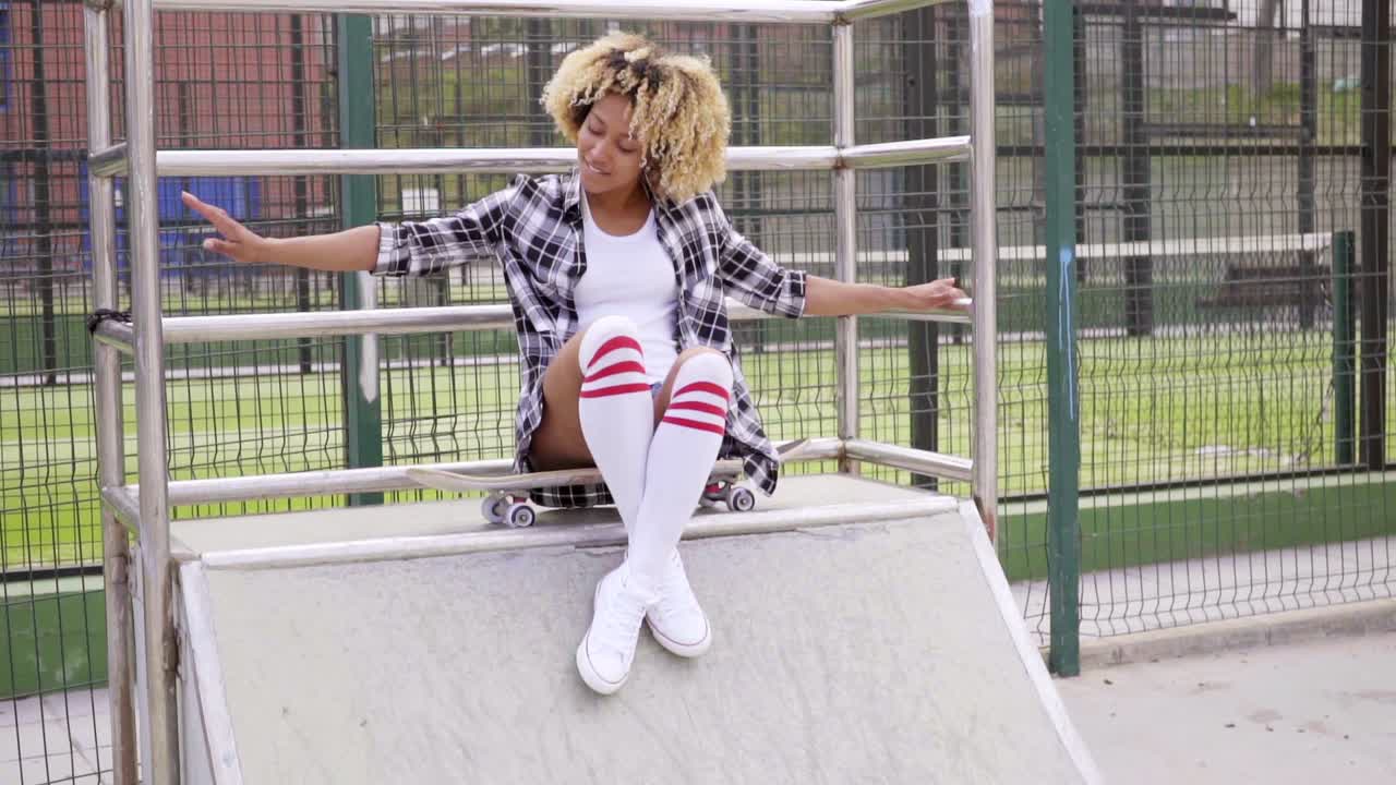 Giovane donna carina e divertente in posa su uno skateboard.