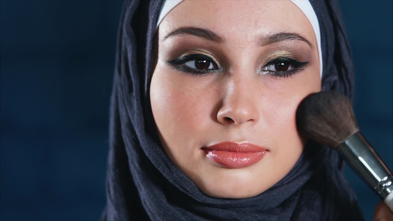 Woman Applying Makeup in Hijab