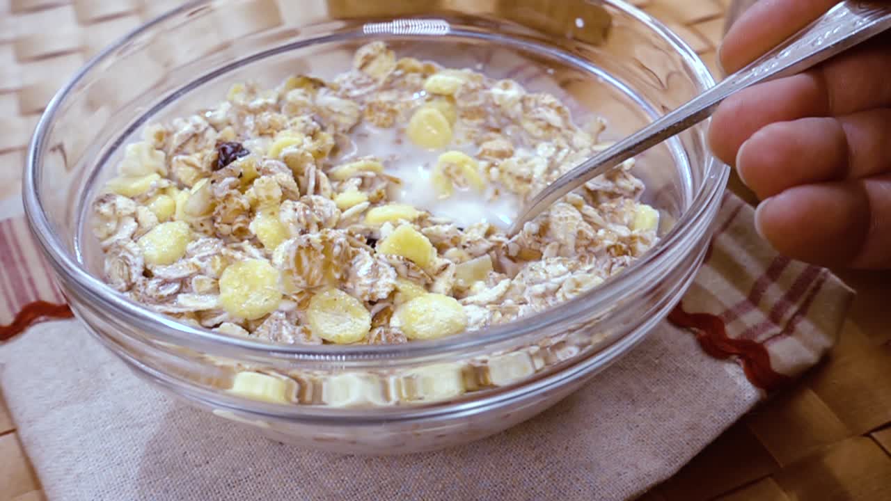muesli de cereales de grano entero en un tazón para un delicioso desayuno matutino con leche. cámara lenta con toma de seguimiento de rotación.