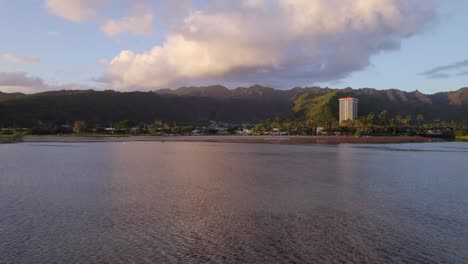 Imágenes-De-Drones-En-Movimiento-Lento-Del-Este-De-Honolulu-Hawaii-Desde-La-Perspectiva-Del-Agua-Con-El-Brillo-Rosado-Del-Sol-Poniente-Reflejándose-En-El-Agua-Y-Las-Nubes-Hinchadas