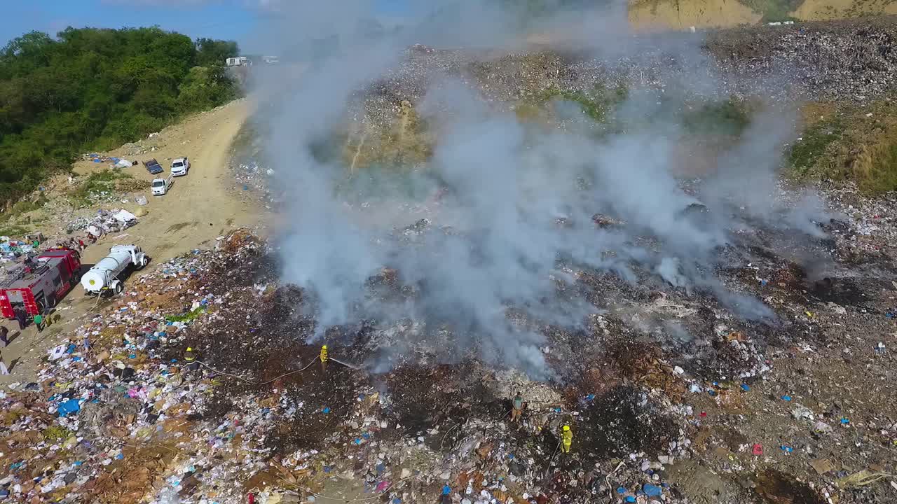 폐차장의 화재를 진압하기 위해 호스를 사용하는 소방관 - 공중 드론 보기