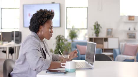 Afroamerikanische-Geschäftsfrau,-Die-Im-Büro-Zu-Mittag-Isst-Und-Einen-Laptop-Benutzt,-Zeitlupe