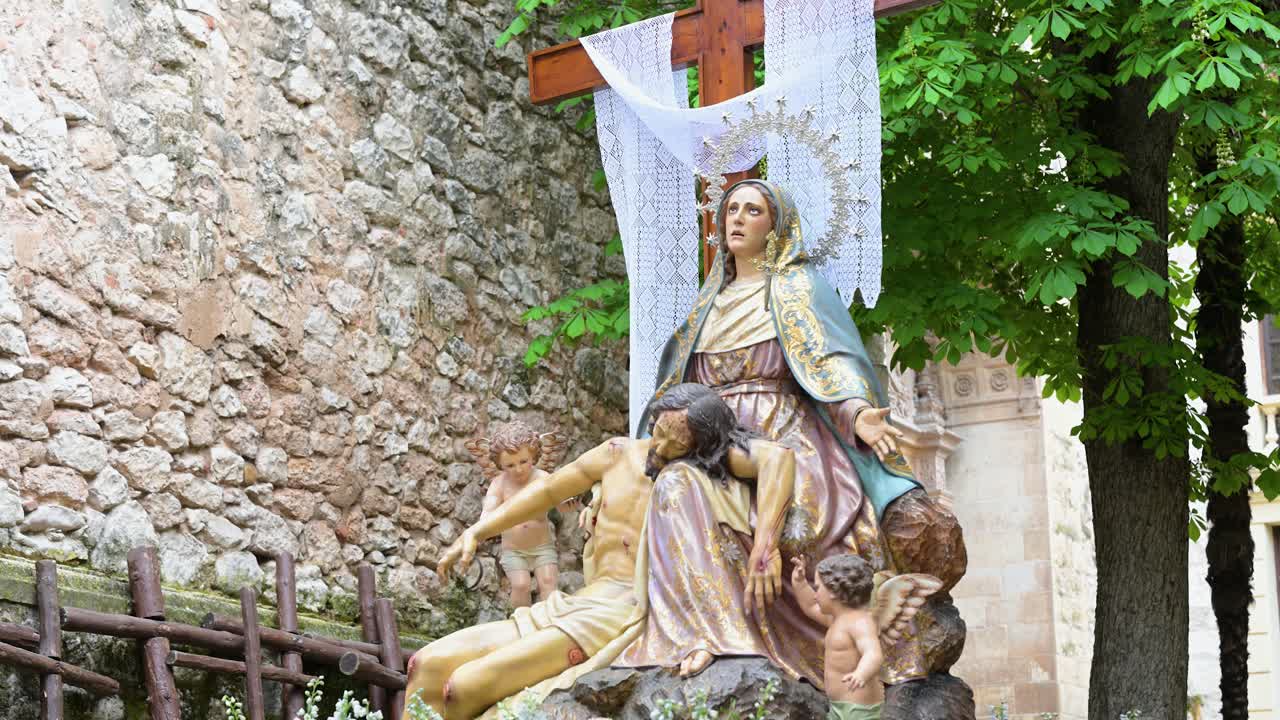 A lavish Pietà float, adorned with flowers, stands ready for an Easter procession in Guadalajara, Spain. It powerfully conveys Spanish religious tradition, artistry, and deep spiritual devotion.