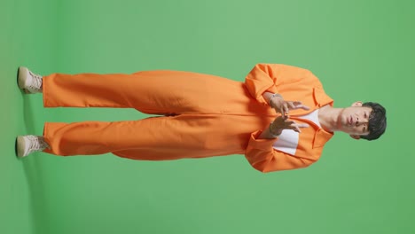 full body of wondering asian male prisoner in handcuffs standing doubtfully on the green screen background, raising hands in anger and shouting why