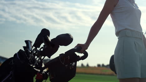 golf person taking clubs bag trolley in country club. woman walk golfing course.