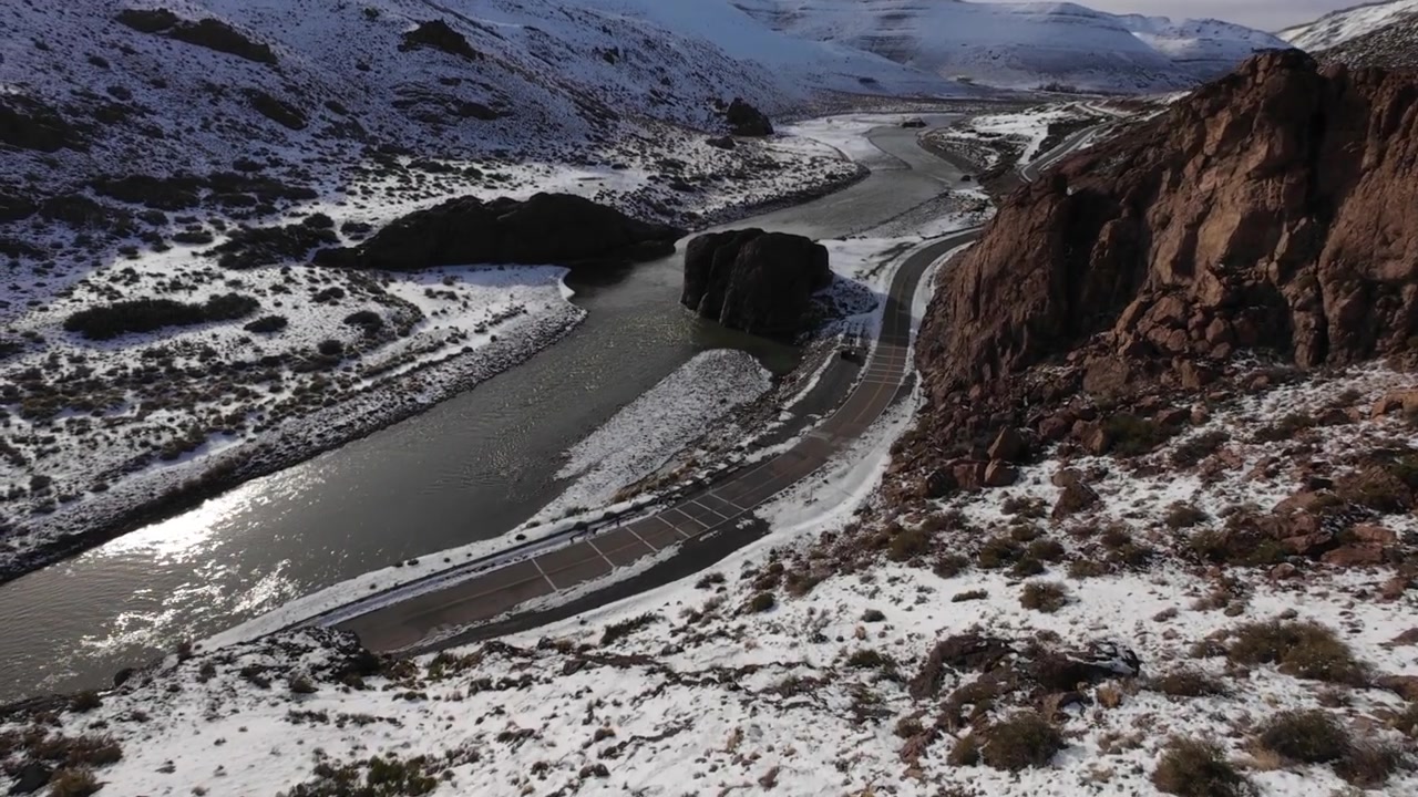 Fast FPV drone flight over snowy canyon and mountain road at Paso Pehuenche in Mendoza province.
