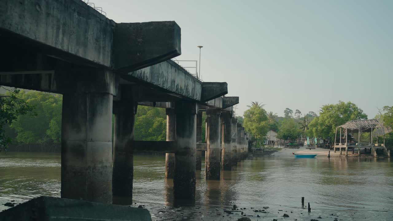 Weathered Concrete Bridge Above Low Tide River in Rural Thailand