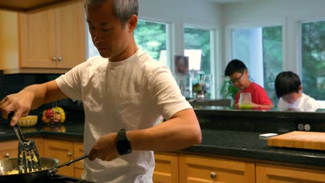 Padre-Cocinando-Comida-Mientras-Sus-Hijos-Juegan-En-El-Fondo-4k