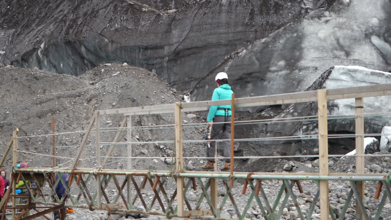 Person in rock climbing gear, crossing bridge in Iceland