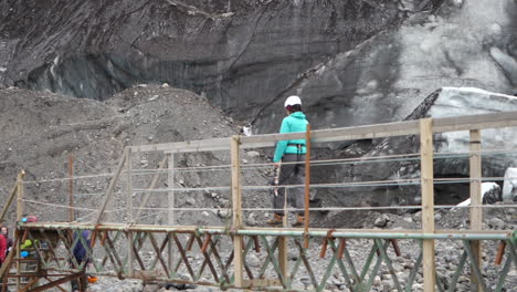person in rock climbing gear, crossing bridge in iceland