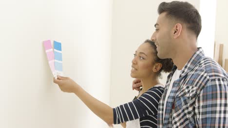 Pareja-Joven-Tratando-De-Elegir-Un-Color-De-Pintura