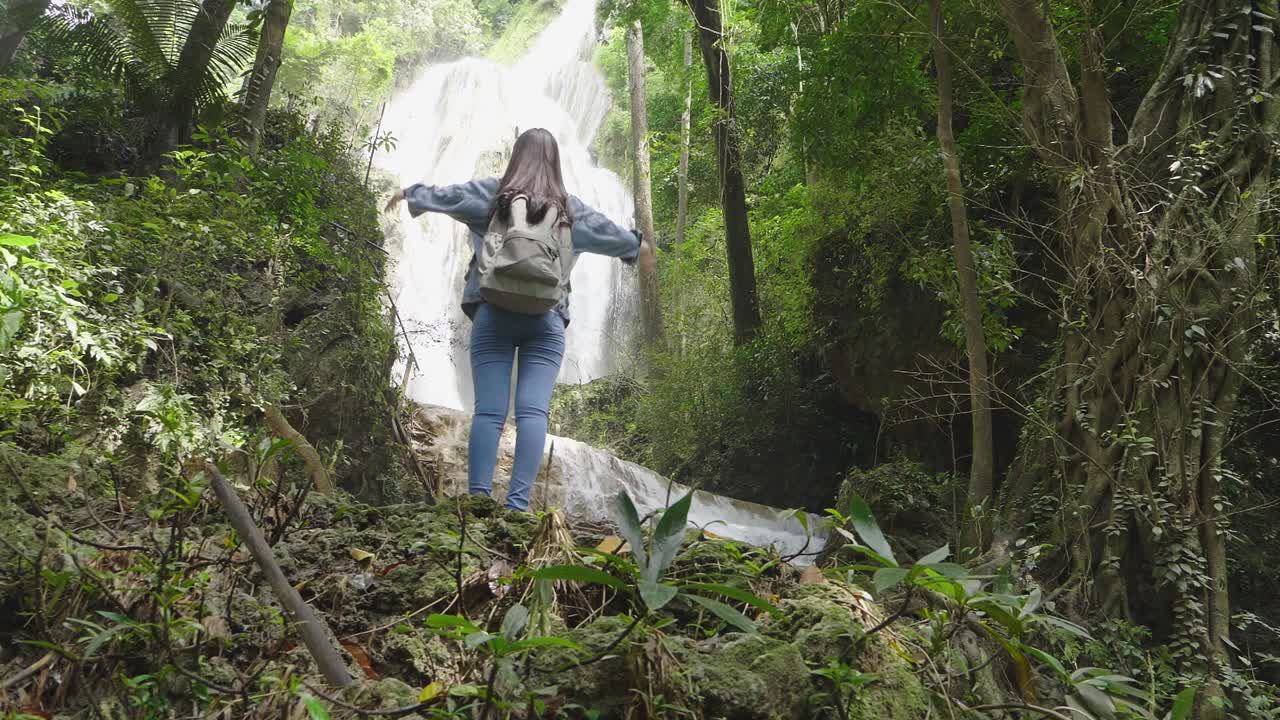 Woman enjoying a waterfall in the jungle