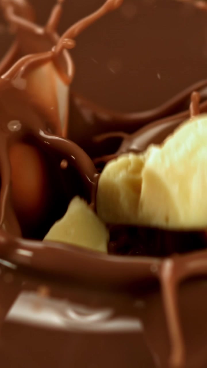Pezzi di cioccolato bianco che cadono nel cioccolato al latte fuso al rallentatore