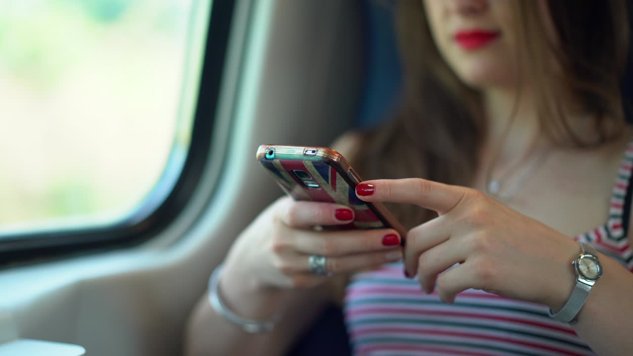 mujer joven viajando en tren o metro jugando y pasando el tiempo en su teléfono inteligente. 4k (uhd) clip de una mujer joven usando su teléfono mientras viaja en el tren de metro. tren llegando al destino o estación